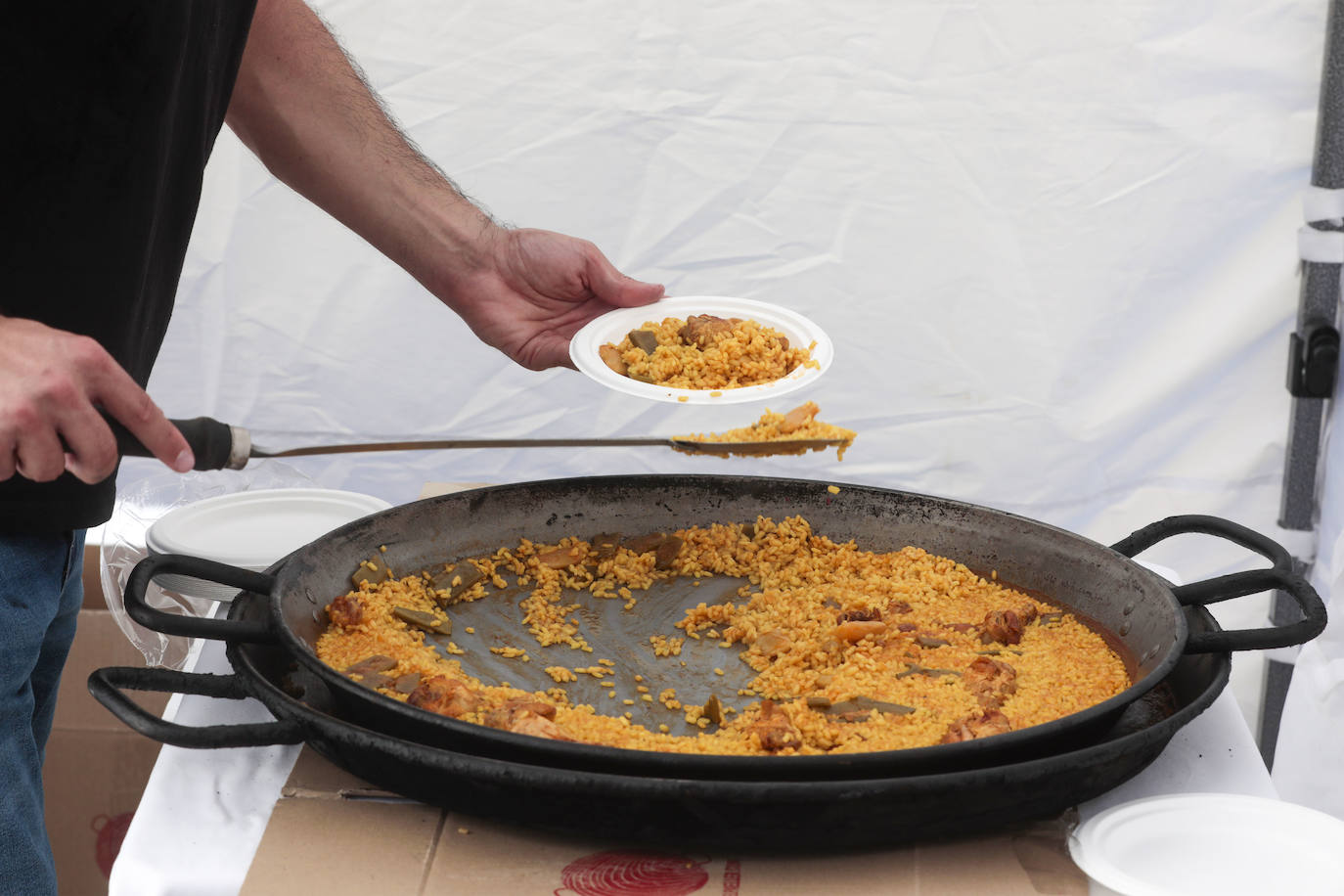 Un cocinero sirve un plato de paella.