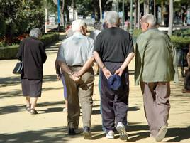 Unos jubilados conversan mientras pasean por un parque