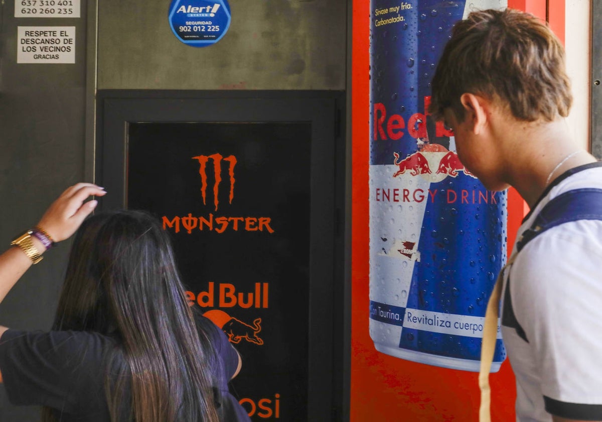 Dos adolescentes frente a una máquina de bebidas energéticas.