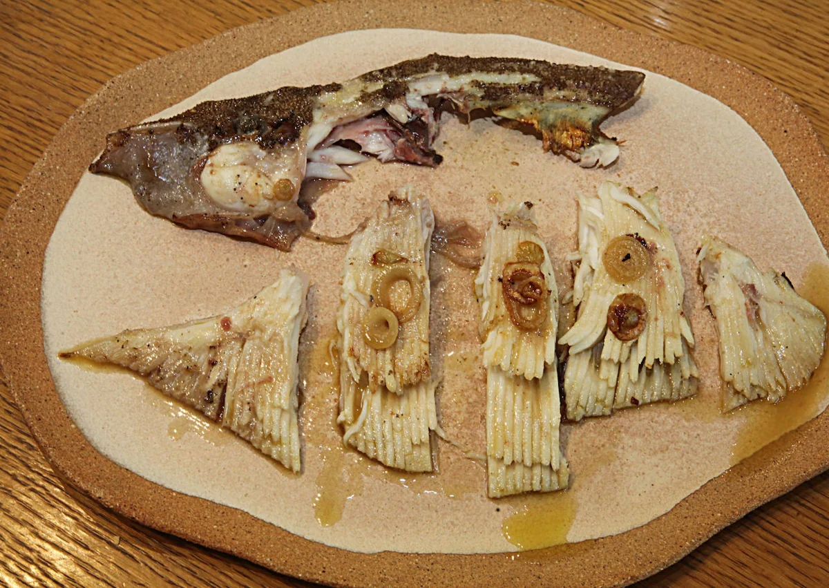 Imagen secundaria 1 - Miquel Gilabert preparando raya, el pescado emplatado e Irene regando el pan con aceite de Benasau.