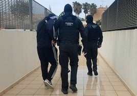 Dos guardias civiles trasladan a uno de los detenidos.