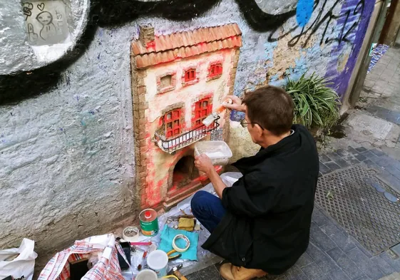 Alfonso Yuste, reparando la fachada de la casa de los gatos.