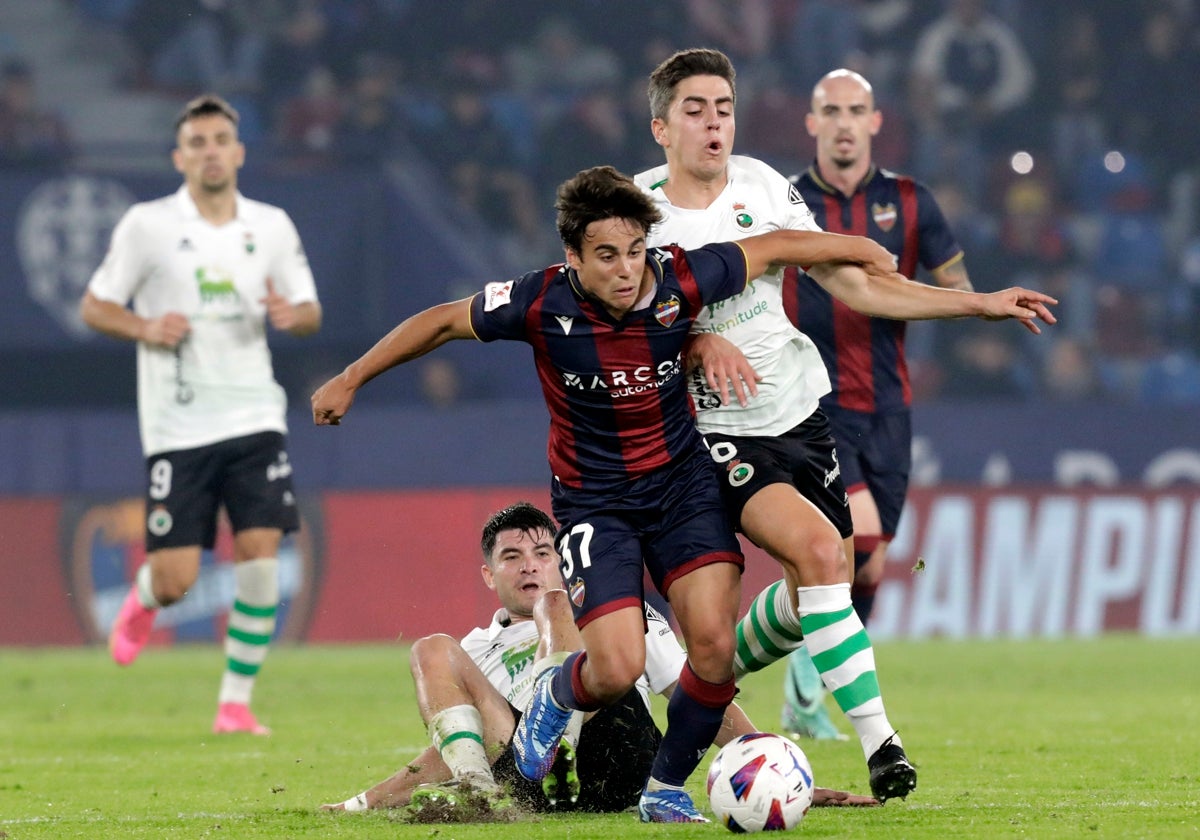 Carlos Álvarez intenta zafarse de dos jugadores del Racing de Santander.