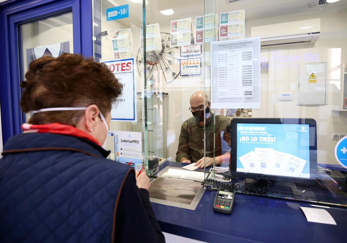 Una señora compra un décimo en una administración de Loterías.