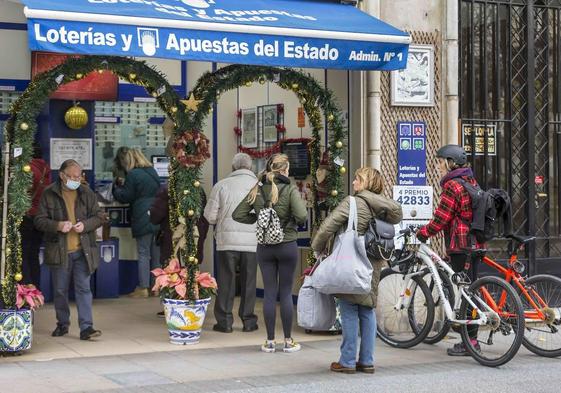 Un grupo de personas hace cola para comprar lotería.