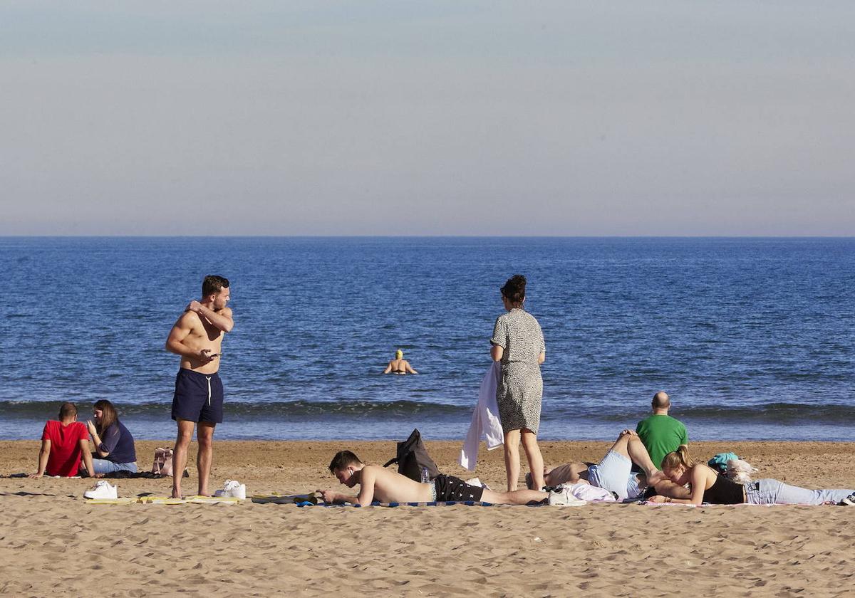 Varias personas aprovechando la inusuales temperaturas de estos días en Valencia para darse un baño en la playa.