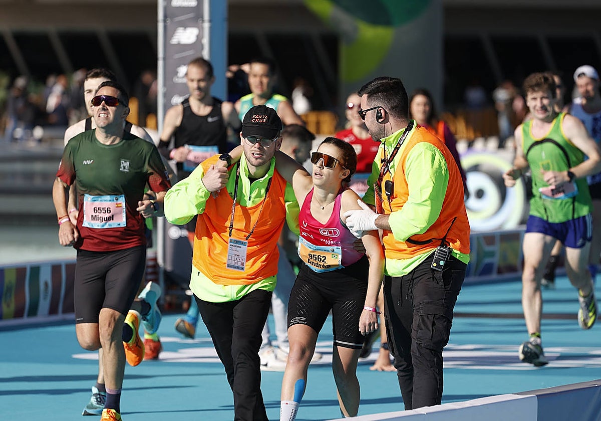 Una corredora es atendida a pocos metros de finalizar el Maratón de Valencia.