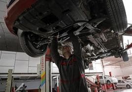 Un mecánico repara un vehículo en un taller.