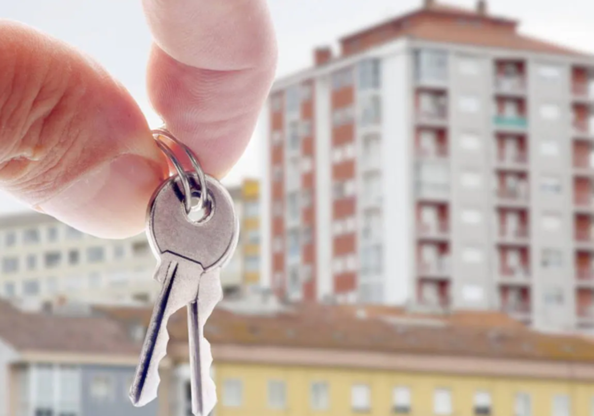 Un propietario muestra las llaves de un inmueble frente a un edificio.