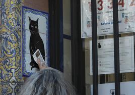 Una mujer frota un décimo recién comprado en la Administración de Loterias del Gato Negro de Sevilla.