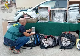 Un agente de la Guardia Civil agrupa los paquetes de droga confiscados a la supuesta organización criminal.