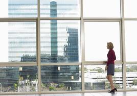 Una mujer mira por la ventana desde su lugar de trabajo.