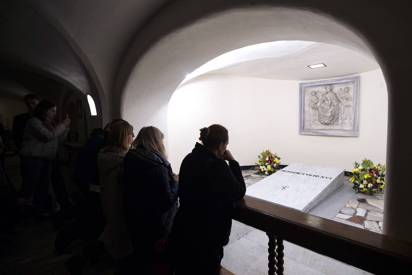 Tal y como estaba previsto, después de las obras efectuadas para la introducción en la cripta del ataúd, las puertas de este área situada en los sótanos de la basílica de San Pedro han reabierto de nuevo a los turistas y los fieles. Los restos mortales de Benedicto XVI, que reposan en un ataúd triple, el primero elaborado con madera de ciprés, el segundo de zinc y el tercero de roble, junto con algunos objetos personales, como las medallas acuñadas durante su pontificado o un pergamino con los hechos más destacados de su vida como la lucha contra los abusos sexuales, fueron trasladados este jueves hasta las grutas vaticanas después de su funeral oficiado por el Papa Francisco en la plaza de San Pedro del Vaticano.