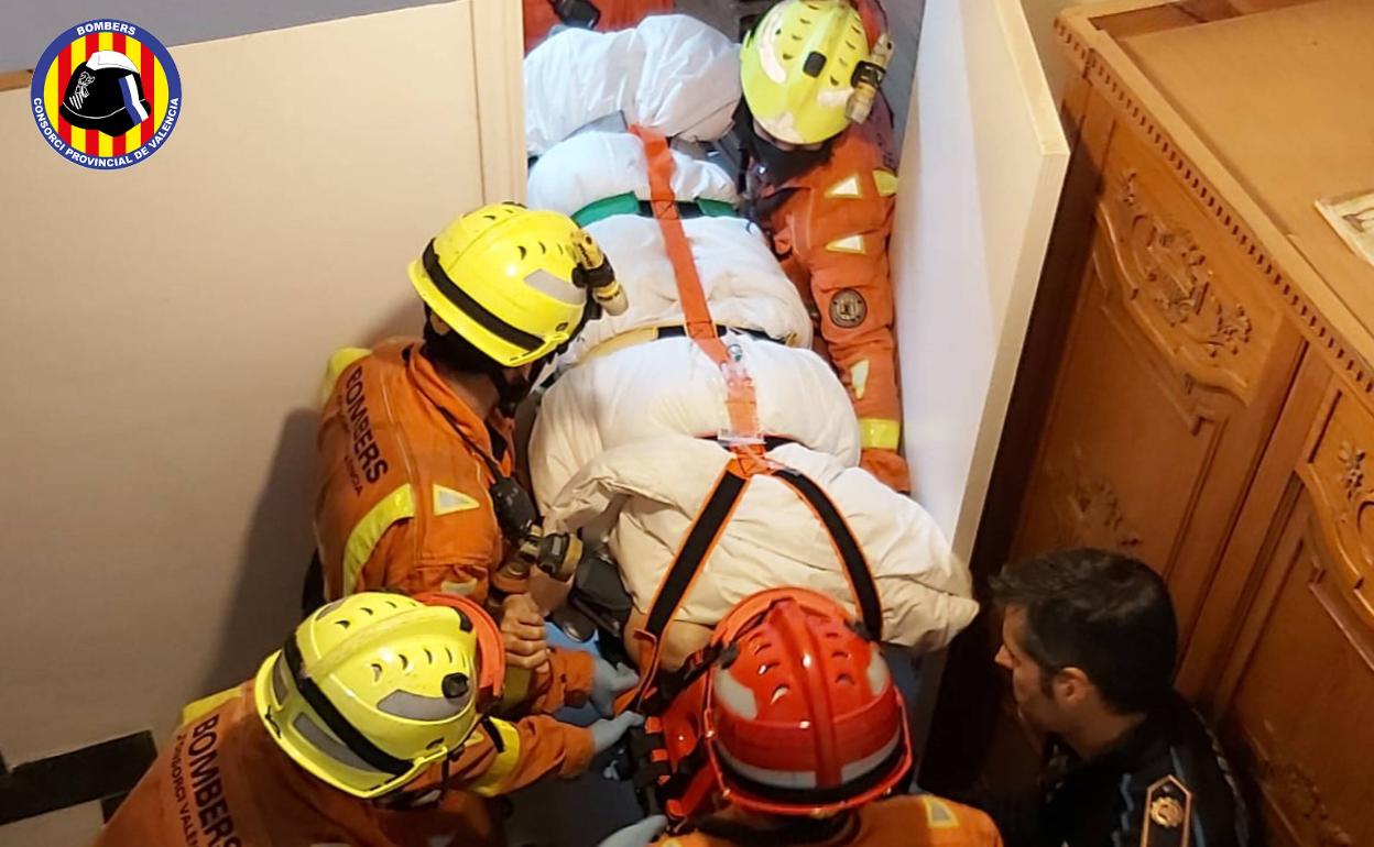 Bomberos y un policía local de Paterna, durante el traslado del hombre herido en una camilla. 