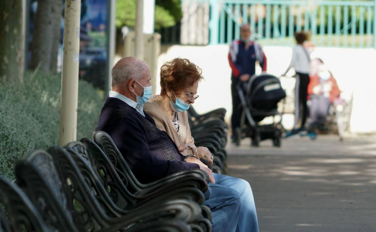 Una pareja de ancianos sentada en bancos