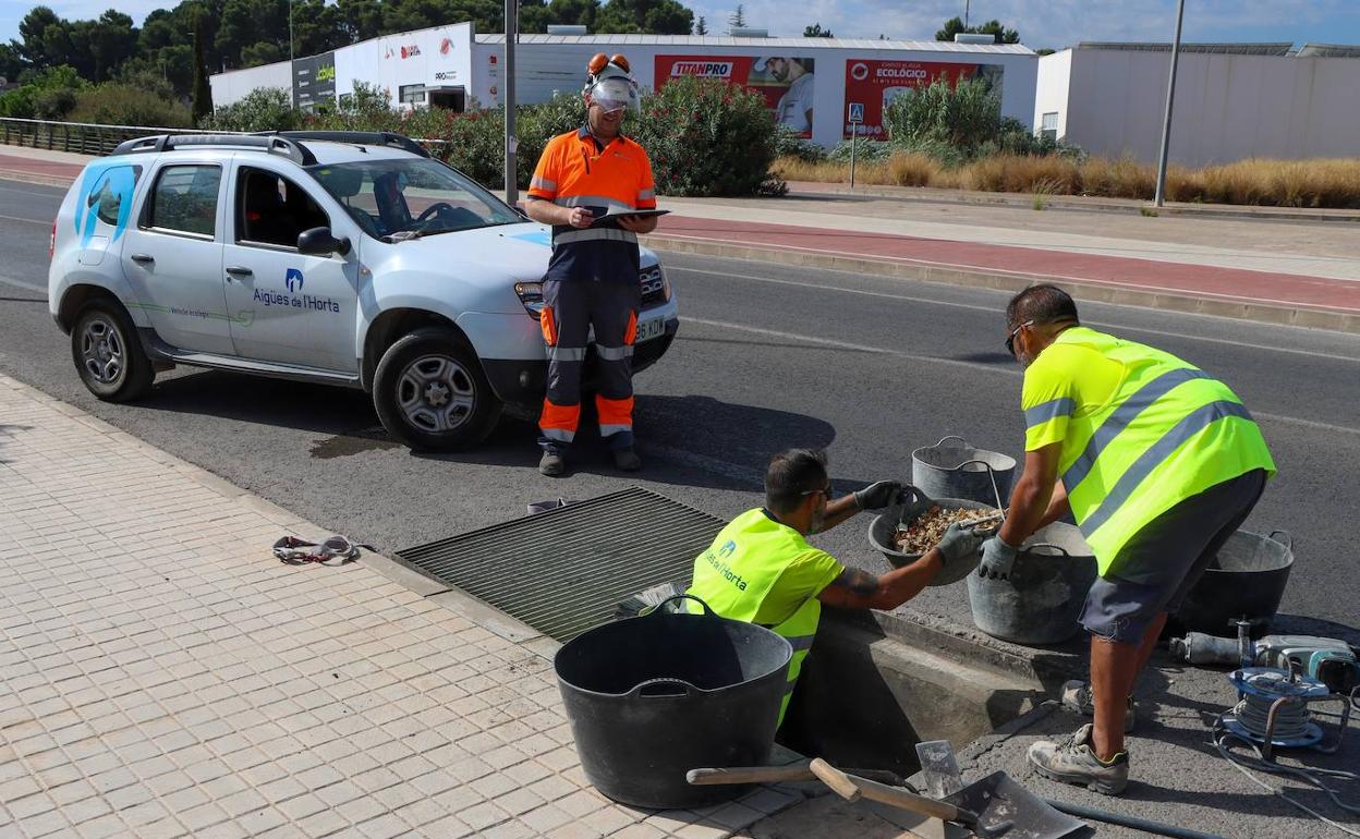 Los trabajadores limpian una alcantarilla. 