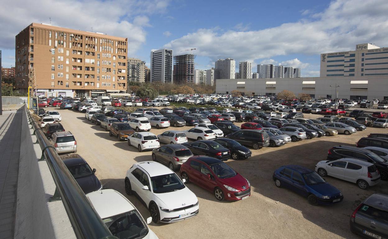 El edificio aislado, al fondo, rodeado de vehículos aparcados. 