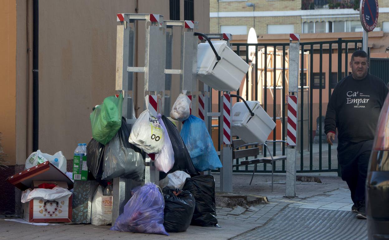 Bolsas de basura y cubos colgados en los totems en la vía pública. 