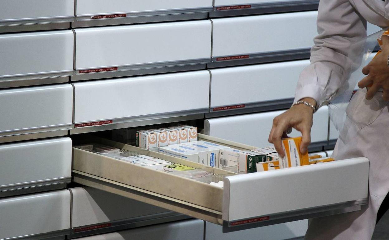 Una trabajadora coloca los medicamentos en el cajón de una farmacia