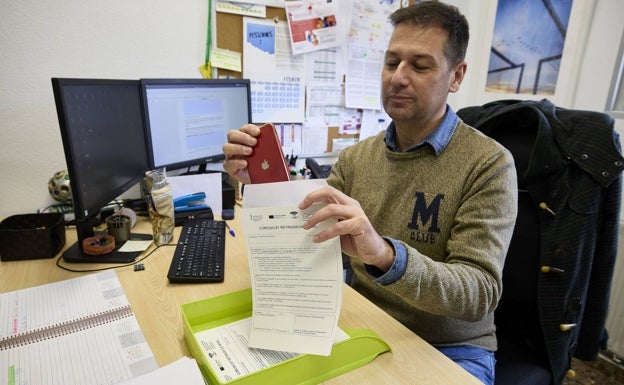 El director del IES Les Alfàbegues de Bétera, Luis Giménez, muestra una hoja de intervención escolar del móvil, junto a un celular. 