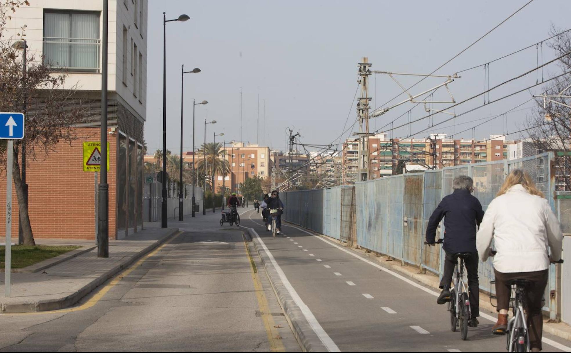 Varios ciclistas recorren el carril bici en la calle Ibiza, junto a las vías del tren. 