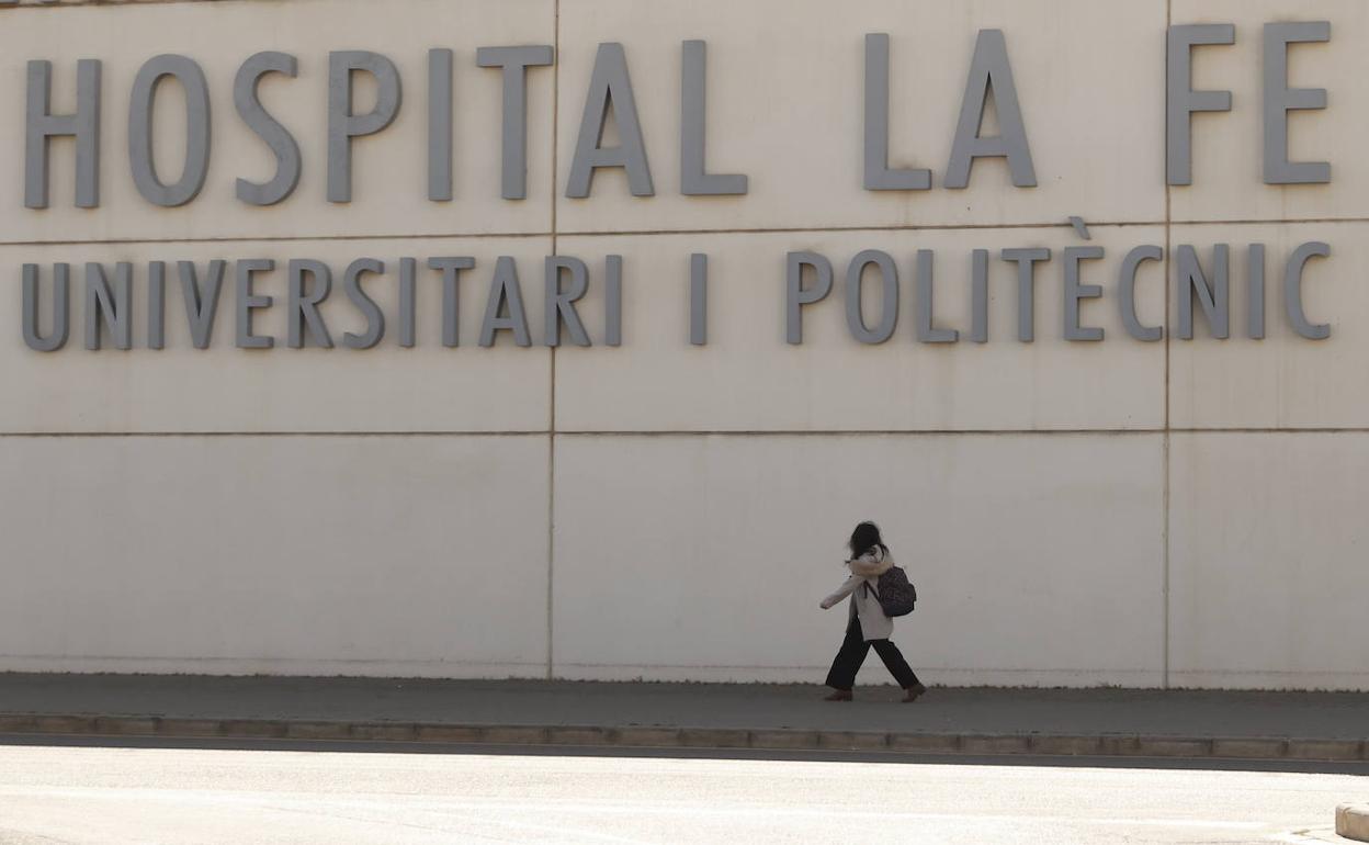 Una persona camina frente a una de las fachadas del hospital La Fe de Valencia.