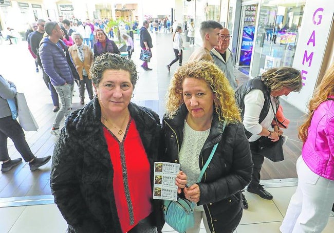 Dos mujeres enseñan los décimos que acaban de adquirir en la administración 'La gran ilusión' situada en el centro comercial Bonaire.