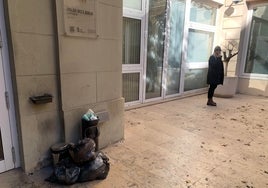 Bolsas de basura apiladas alrededor de papeleras rebosantes en la entrada trasera de Les Corts.