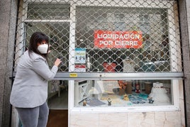 Una comerciante baja la persiana de su tienda durante el confinamiento por el Covid.