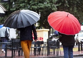 Varios viandantes se protegen de la lluvia con paraguas en Valencia.