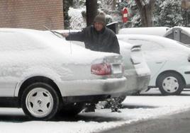 Un hombre retirando el hielo de su coche.