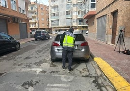 Un policía sale del apartamento del canónigo en el Perelló con objetos hallados en el piso.