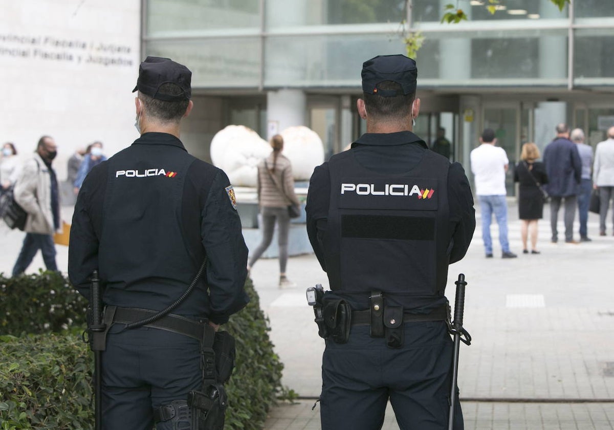 Dos agentes, ante la fachada principal de la Ciudad de la Justicia.