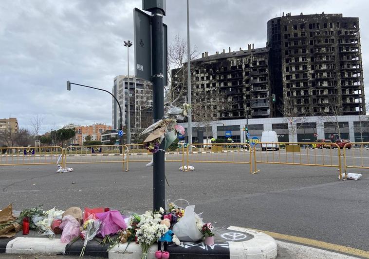 Flores, velas y algún peluche depositados ante el edificio incendiado.