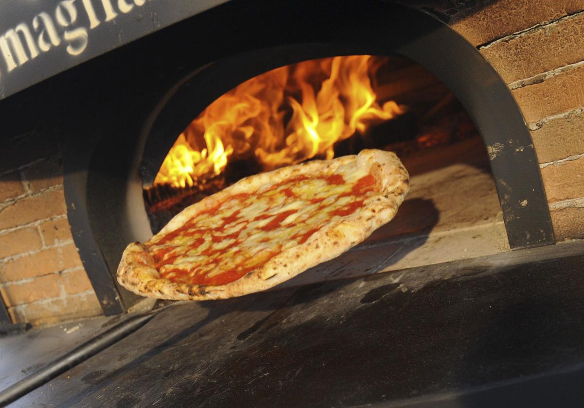 Una persona sacando una pizza del horno.