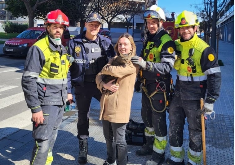 Andrea posa con 'Coco', los bomberos y el policía que han encontrado al gato.