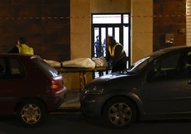 Un empleado del retén fúnebre judicial traslada el cuerpo sin vida de la víctima, el jueves, en la calle Brasil de Valencia.