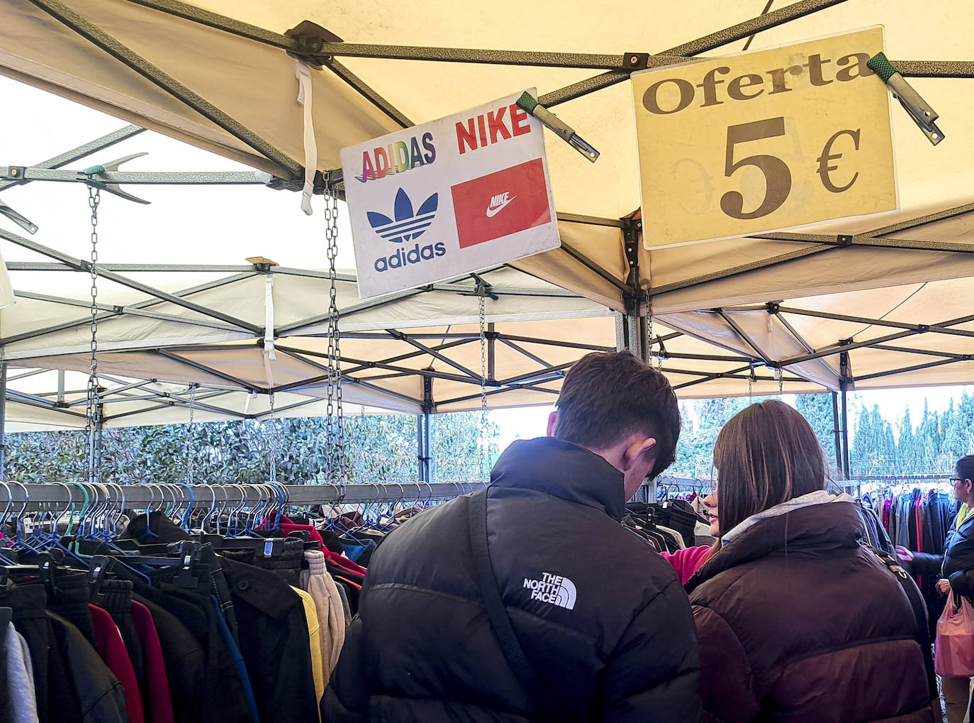 Dos jóvenes comprando productos falsificados en el mercadillo de Benaguassil.