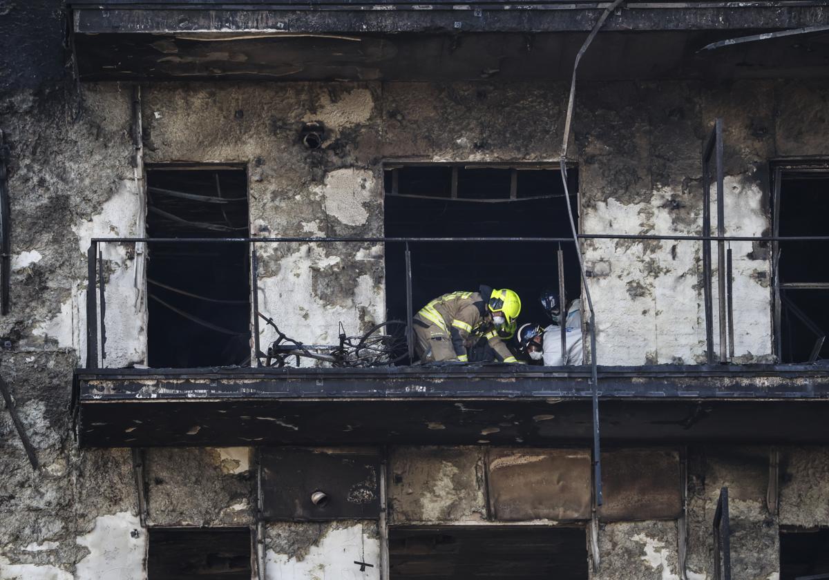 Un bombero y un policía investigan el interior del edificio incendiado en Campanar