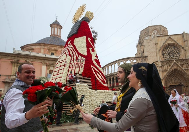 Una joven entrega a un vestidor el ramo de flores de la Ofrenda. I