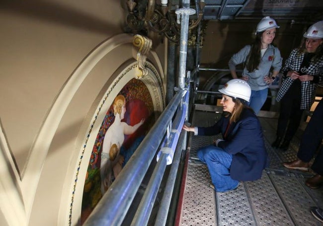 La alcaldesa observa una de las pinturas situadas encima de las puertas de entrada.