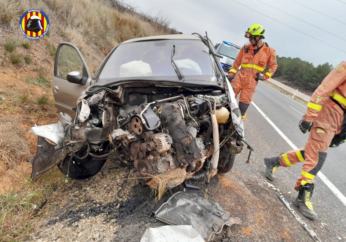 Los bomberos trabajan junto al vehículo siniestrado esta tarde en la A-3 a su paso por Requena.