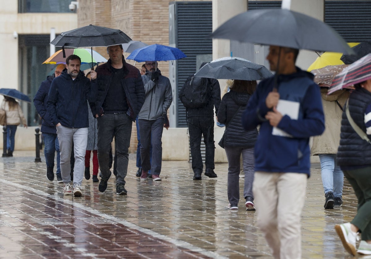 Viandantes se protegen con paraguas de la lluvia de este lunes.