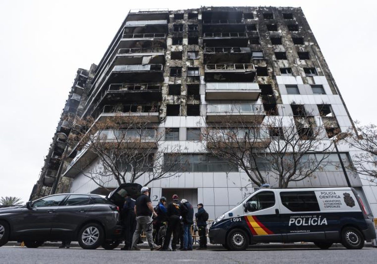 Investigadores privados y policías junto al edificio destruido por el fuego.