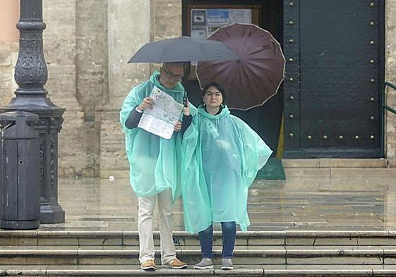Dos turistas se refugian de la lluvia en una imagen de archivo.