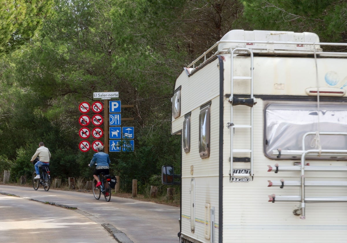 Imagen principal - Cartel donde se indica la prohibición de acampar; picnic entre caravanas y gran camión en el parking de la playa de El Saler.