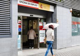 Una mujer con paraguas pasa por la oficina del paro en una imagen de archivo.