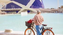 Una turista visita en bicicleta la Ciudad de las Artes y las Ciencias de Valencia.