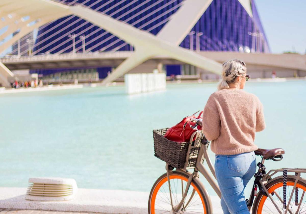 Una turista visita en bicicleta la Ciudad de las Artes y las Ciencias de Valencia.