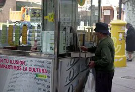 Un hombre compra un cupón en un quiosco de la ONCE.